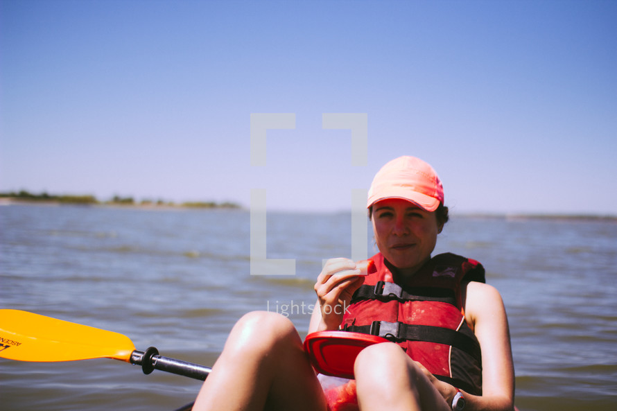woman eating a snack on a kayak 