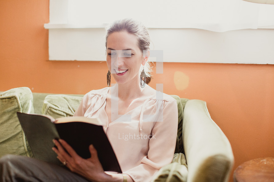 woman reading a Bible on the couch 