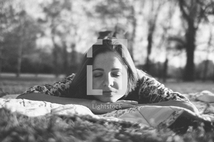 woman resting on a blanket in the grass