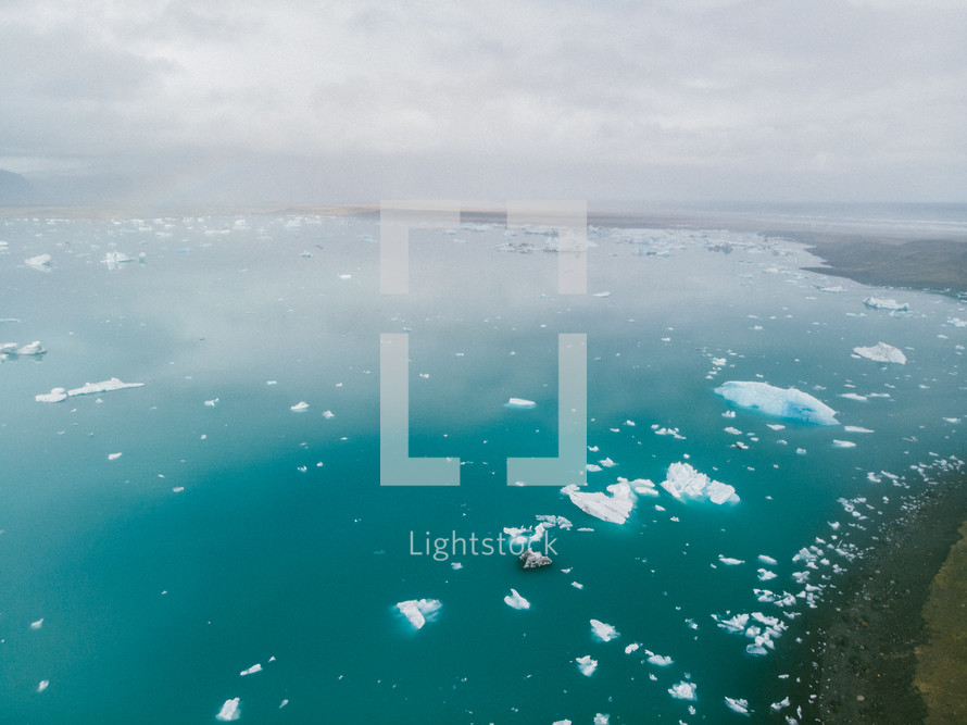 aerial view over chunks of ice floating in the ocean 