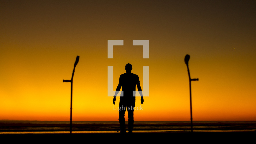 silhouette of a man standing on a beach and arm braces 