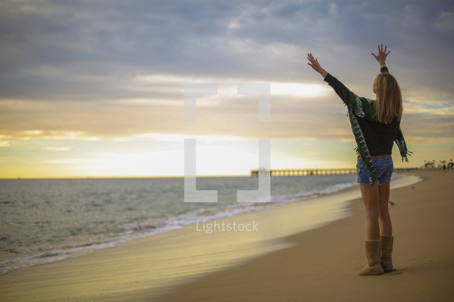 woman with raised hands on a beach 