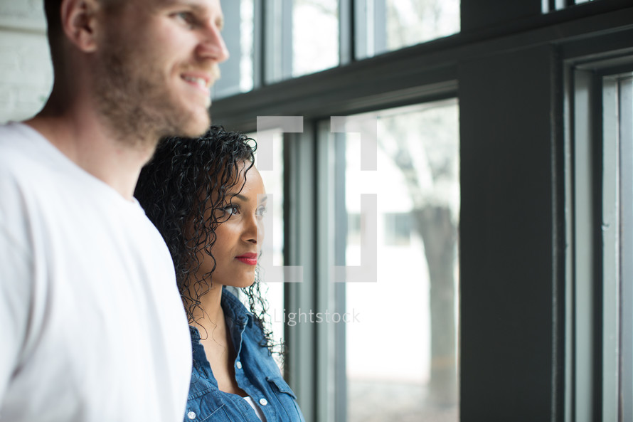 A young man and woman looking out of a window.