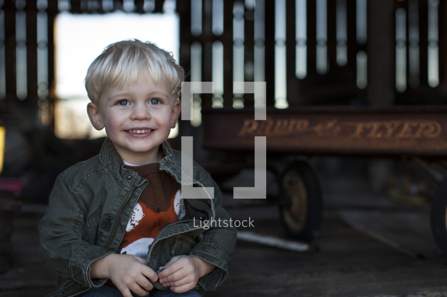 A toddler boy and a radio flyer wagon. 