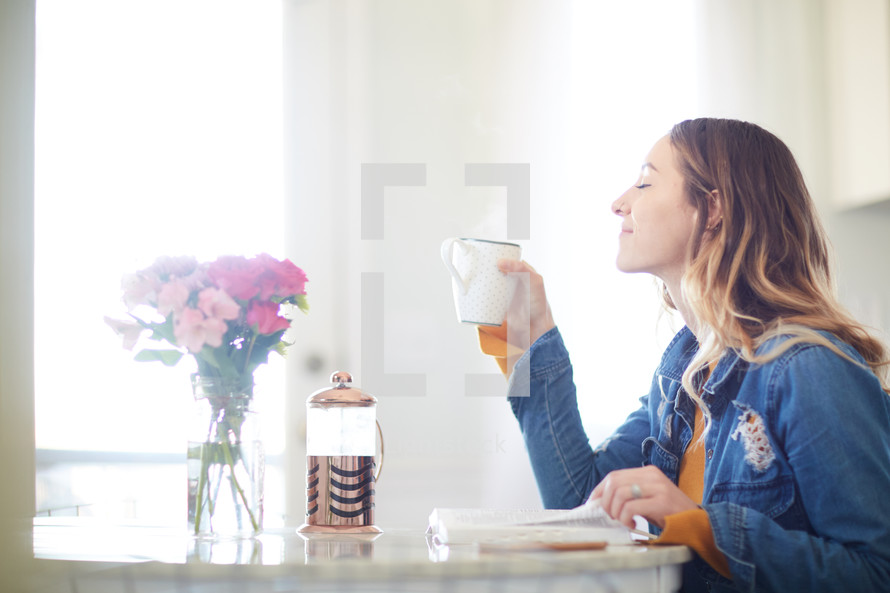 a woman reading a Bible and drinking coffee 