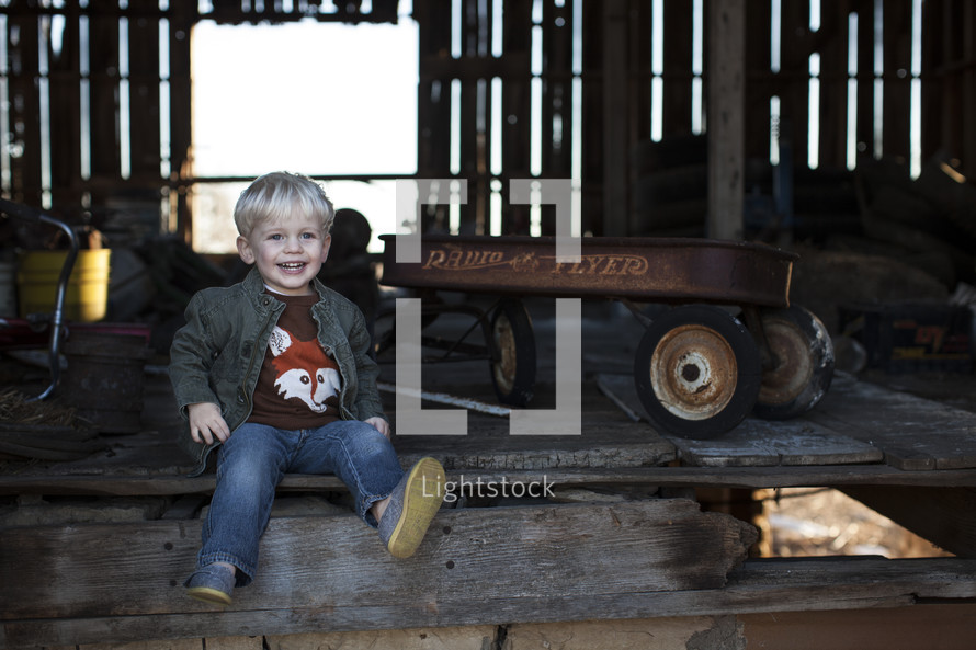 A toddler boy and an old radio flyer wagon. 