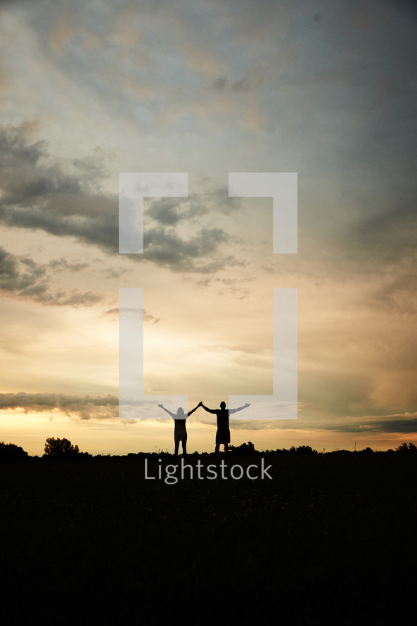 silhouettes of a couple with raised hands 
