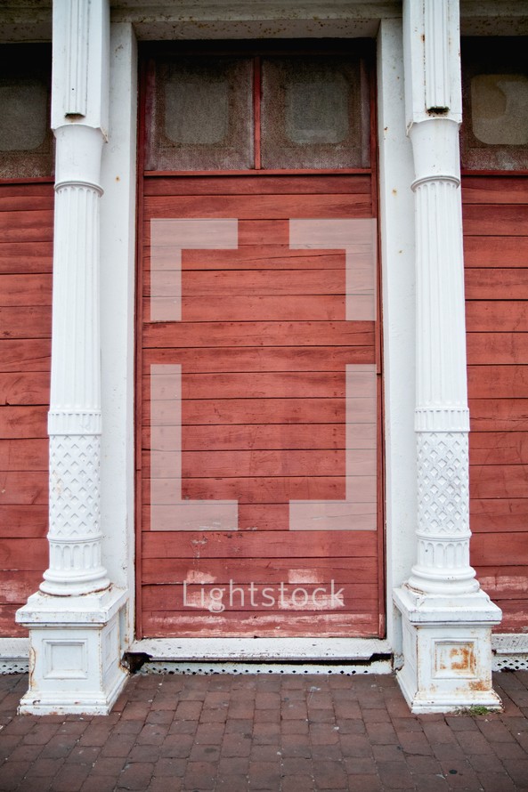 red stained wood planks on an exterior wall and white columns