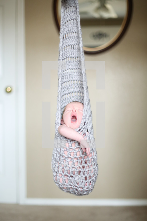 a newborn in a crochet sack 