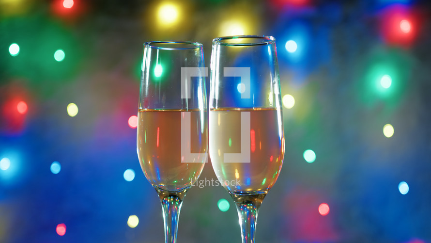 glasses of champagne under colorful lights background 