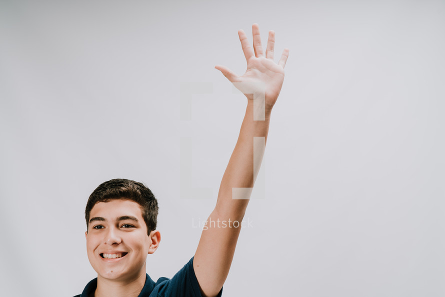 teen boy with hand raised 