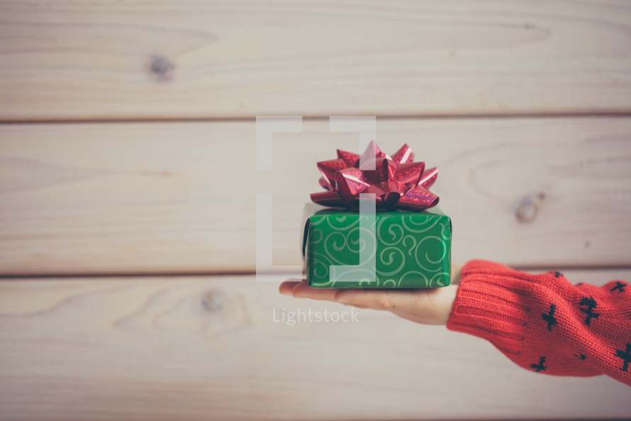 a woman holding out a wrapped Christmas present 