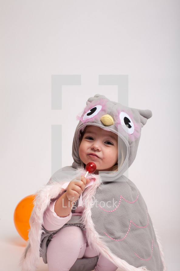 a girl toddler in a Halloween costume with a sucker 
