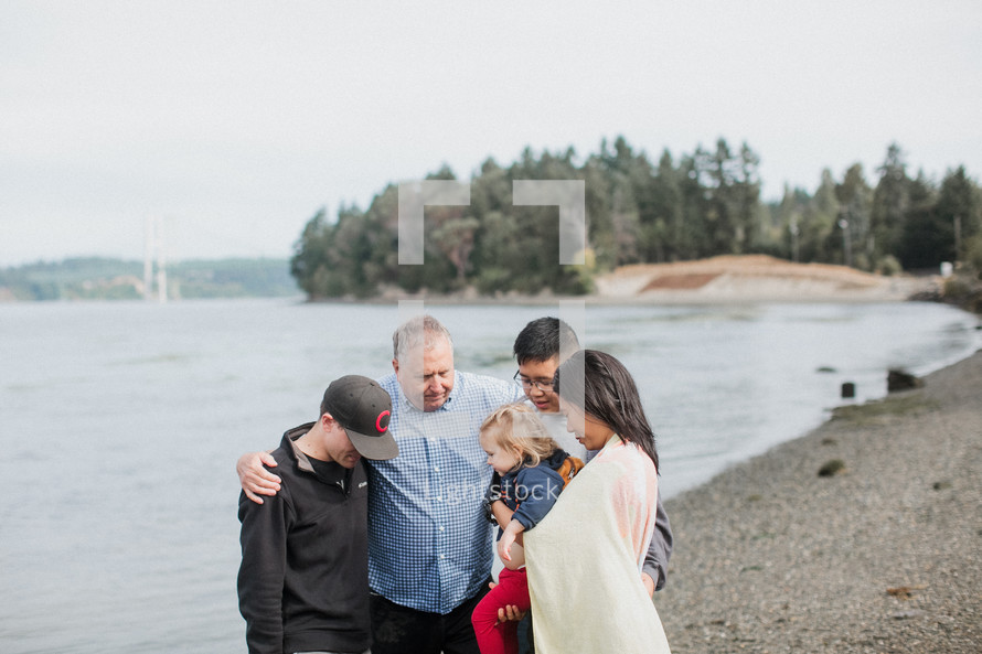 a pastor praying with a family before a baptism in a river outdoors 