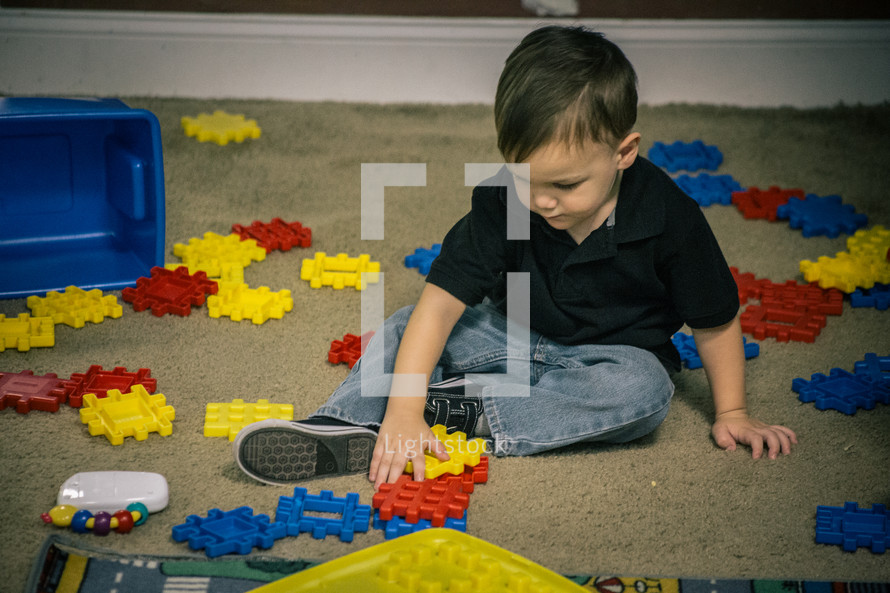 A little boy playing with plastic blocks.