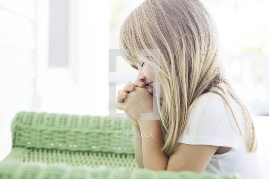 little girl kneeling and bowing her head in prayer.