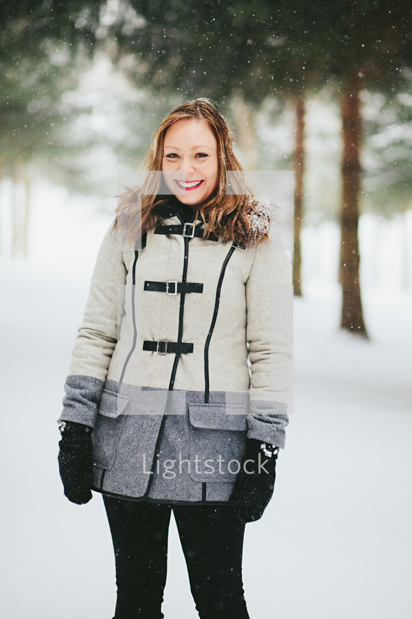 a woman in a coat standing in the snow 