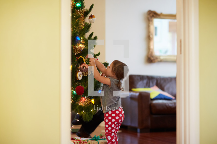 a toddler decorating a Christmas tree