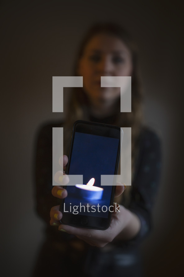 young woman holding image of tiny candle in dark room