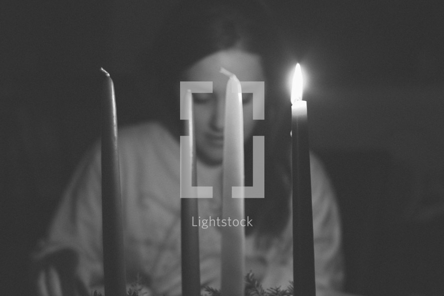 a woman praying behind candlelight 