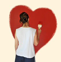 Woman painting a red heart on a wall.