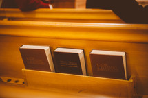 Bible and hymnals on the back of a church pew 