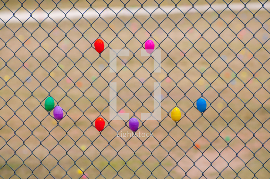 Plastic Easter eggs in a chain link fence.