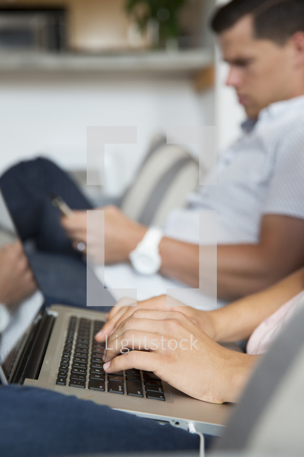 a woman sitting on a couch next to a man while typing on a laptop computer 