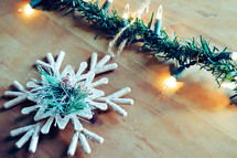 snowflake Christmas ornament and Christmas lights on wood 