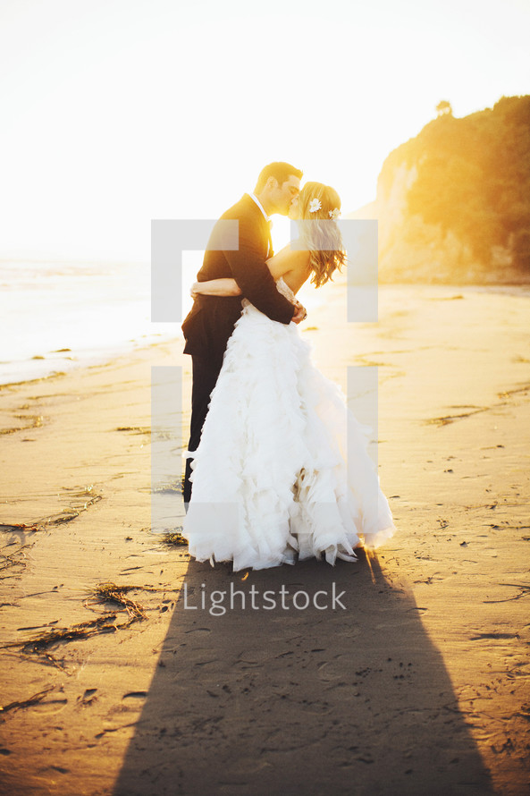 bride and groom kissing on a beach