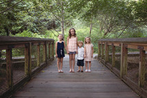 brothers and sisters standing on a wood boardwalk holding hands 