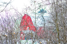 red barn in winter through branches 