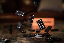 Dominoes frozen in midair as the pieces fall to a table