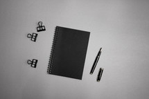 Black notebook with office supplies on gray background