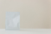 white packet against a tan background 
