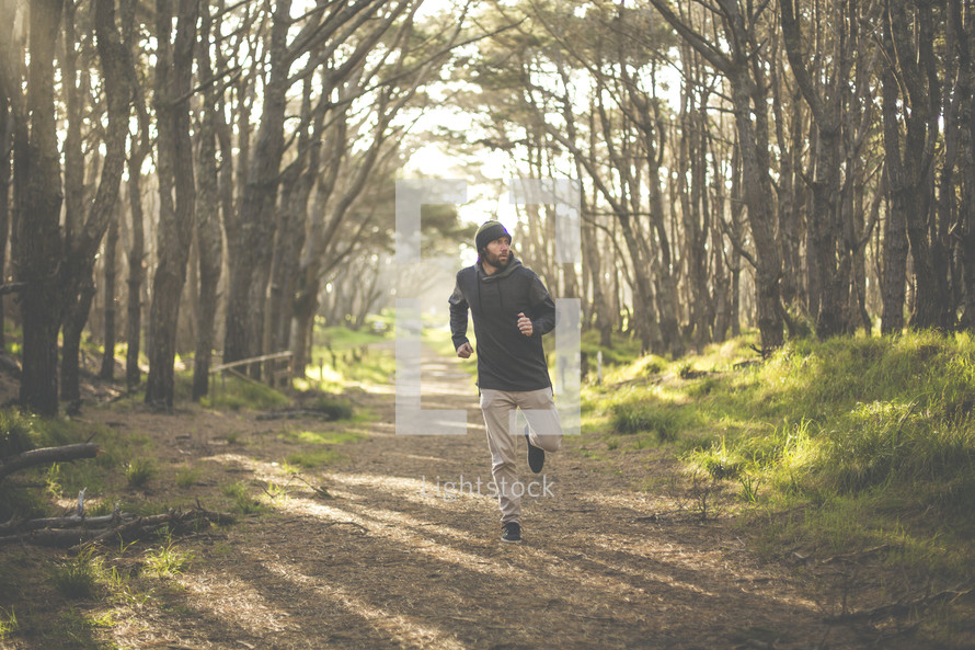 a man running on a path in a forest 