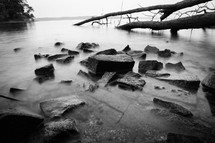 Black and white photo of misty rocks on a lake 