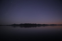 Mountains beside a calm body of water at dusk.