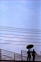 silhouette of a couple with umbrella and power lines 