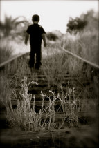 boy child walking on railroad tracks 