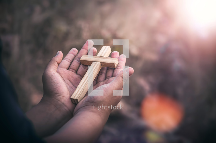 wooden cross in the palm of a hands outdoors 
