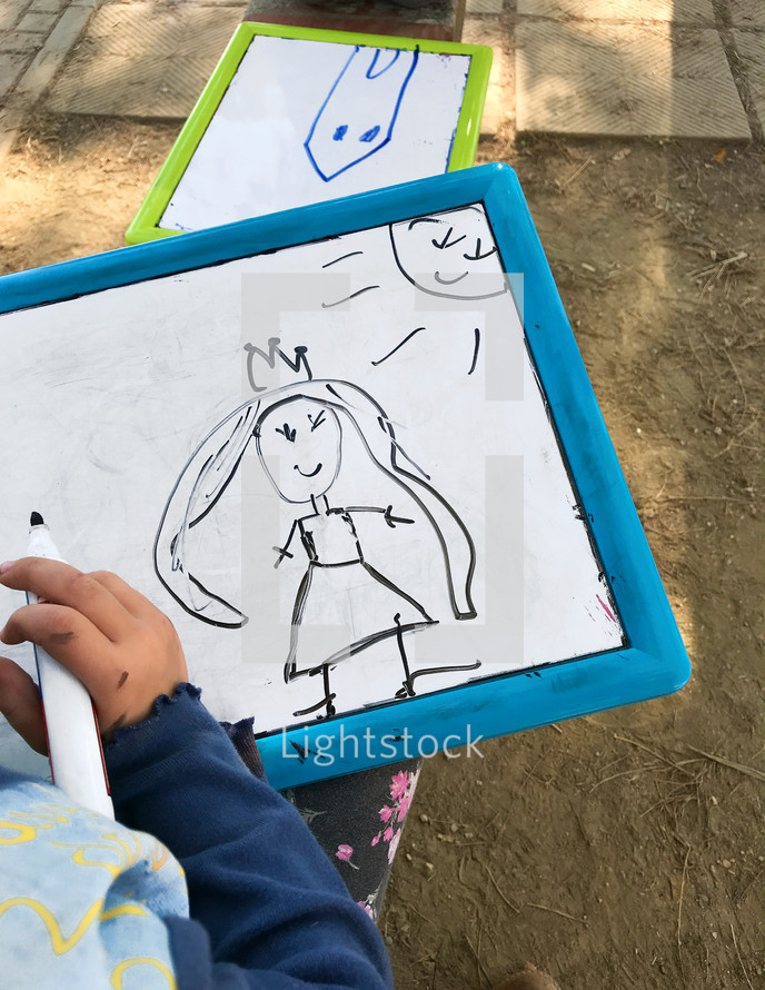 toddler drawing on whiteboards in outdoors.