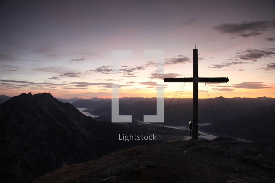 cross on a mountaintop at sunset 