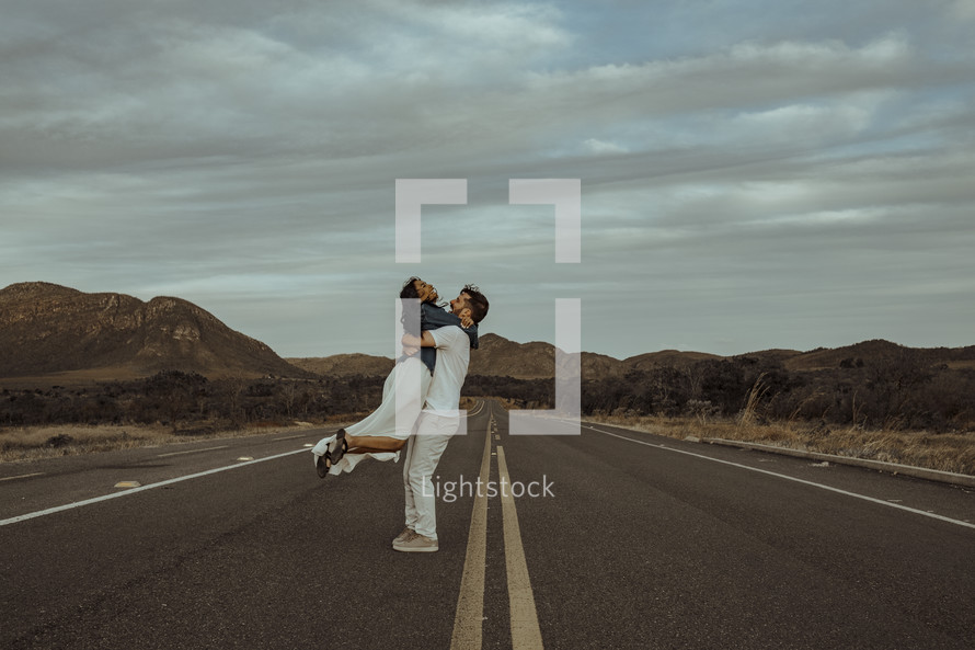 a couple hugging in the middle of a road 
