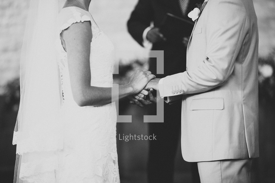 A bride and groom hold hands during the wedding ceremony.