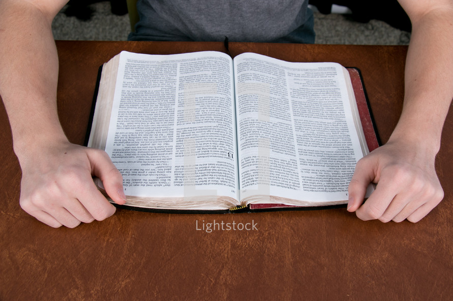 A teen boy reading a Bible. 