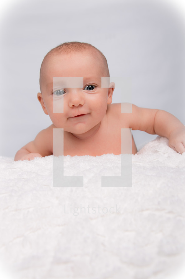 A baby crawling on a white blanket 