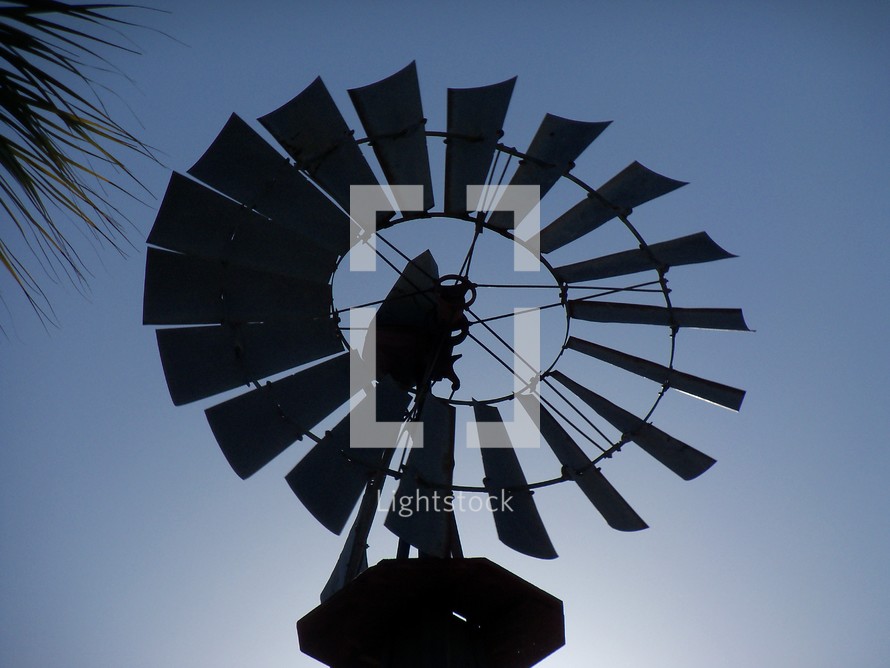 A silhouette image of a large wind mill with its blades reflecting against a night time sky in central Florida. 