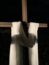 white shroud draped over a cross at night 