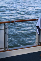 A railing on a boat with water beyond.